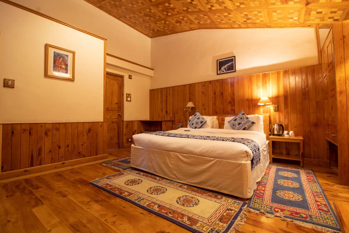 Un dormitorio con paneles de madera, una cama, mesitas de noche y una lámpara de noche.