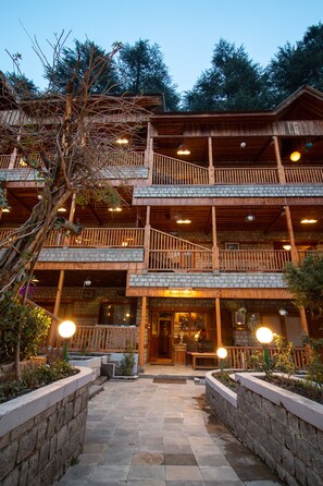 A multi-story wooden building with balconies, stone walls, and a stone-paved entrance area. - Hotel  Negis Mayflower  (Manali)
