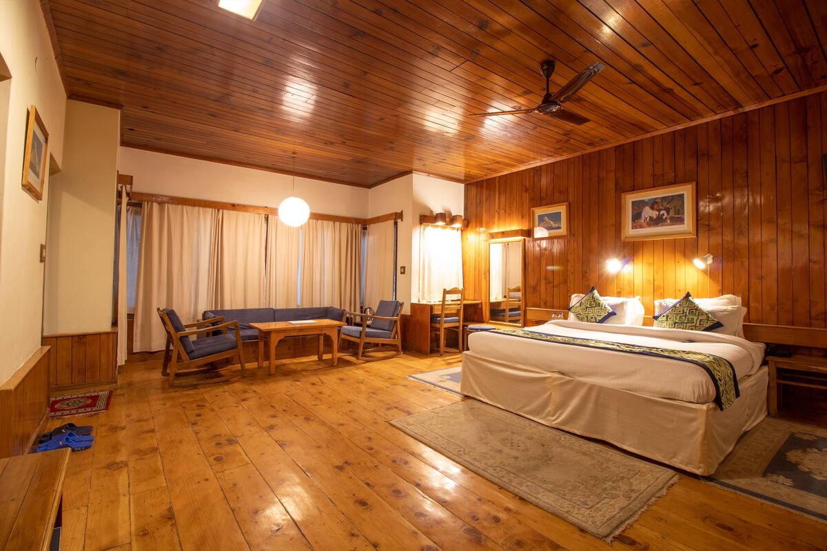Una habitación con paneles de madera, una cama, un sofá, una silla y un escritorio.