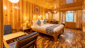A wooden cabin room with a bed, a desk, and a chair. - Hotel  Negis Mayflower  (Manali)