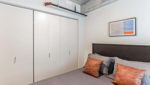 A bedroom with a bed, pillows, a headboard, a wardrobe, and a framed picture on the wall. - Explore Cleveland! Modern Apartment in the City (Cleveland)