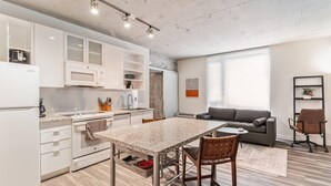 Una cocina moderna con armarios blancos, microondas y un comedor con mesa y sillas.