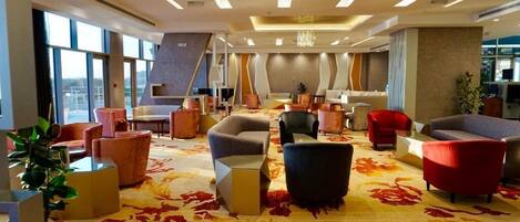 A modern lobby with a variety of seating options, large windows, and a decorative wall.