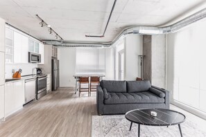 Eine moderne Küche mit weißen Schränken, Edelstahlgeräten und einem Essbereich mit Tisch und Stühlen.
