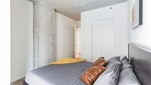Un dormitorio con cama, almohadas, una puerta y un interruptor de luz.
