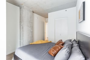 Un dormitorio con cama, almohadas, una puerta y un interruptor de luz.