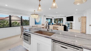 A modern kitchen with a large island, pendant lights, and a view of the outdoors. - 3 bedroom Ocean Front with amazing ocean views! (Saint Augustine)