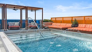 Een zwembad op het dak, met een pergola, zitgedeeltes en uitzicht op de oceaan.