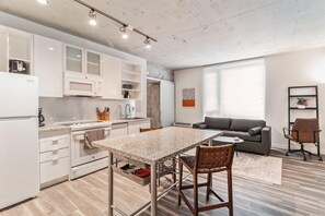 Une cuisine moderne avec des meubles blancs, un four à micro-ondes et un coin repas comprenant une table et des chaises.