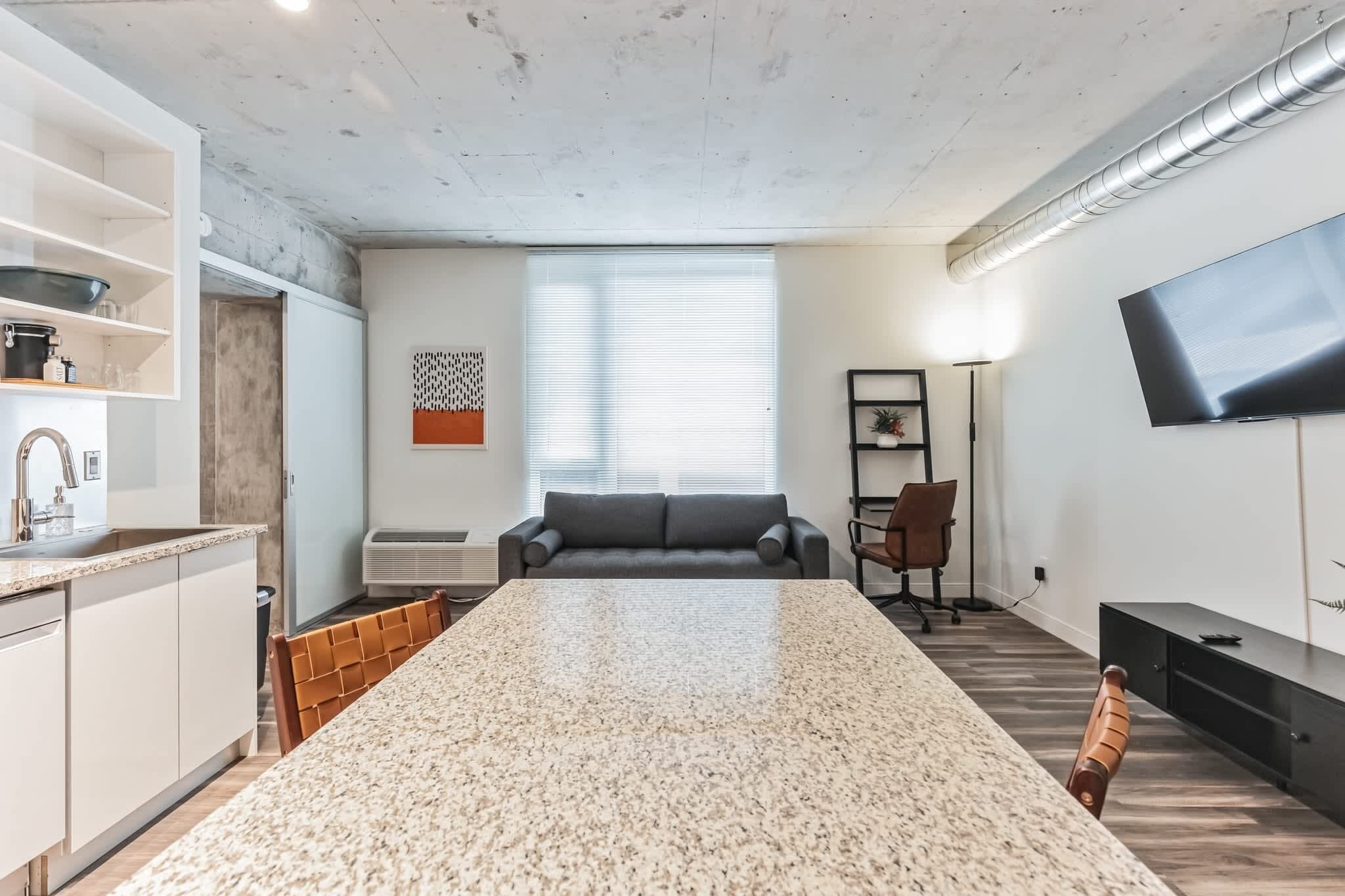 Een moderne keuken met granieten aanrechtbladen, een inbouwoven en een eethoek met een grote granieten tafel.