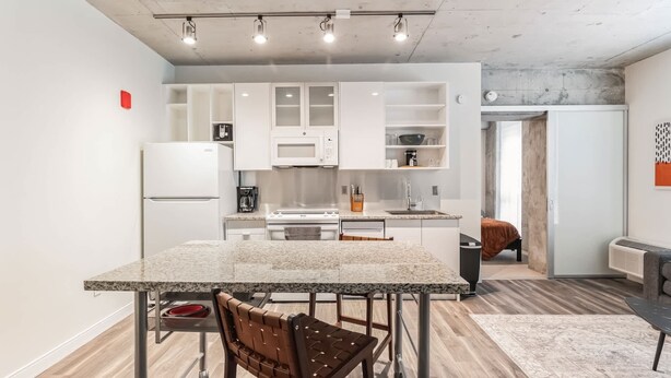 Een moderne keuken met witte kasten, een granieten aanrechtblad en een eethoek met een tafel en stoelen.