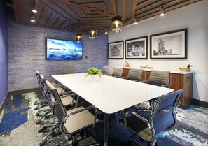 A conference room with a large table, chairs, a TV, framed pictures, and a plant. - Unwind in Comfort—Stylish DT Cleveland Getaway (Cleveland)