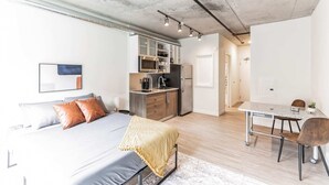 Un appartement moderne doté d’un grand lit, d’une kitchenette, d’un coin repas et d’une salle de bain.