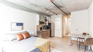 Ein modernes Apartment mit einem großen Bett, einer Küchenzeile, einem Essbereich und einem Badezimmer.