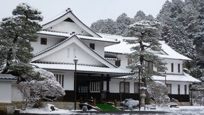 A traditional Japanese-style building with a symmetrical facade, multiple windows, and a snow-covered roof. - Iwamurasansou (Ena)