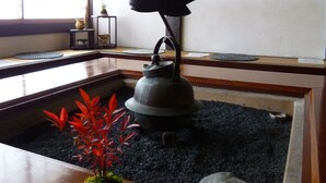 A traditional Japanese room with tatami flooring, a shoji screen, a hanging black lantern, a tea kettle, and a framed calligraphy piece on the wall. - Iwamurasansou (Ena)