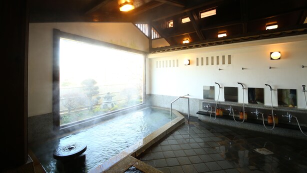 A traditional Japanese onsen with a large hot spring, tiled floor, and a view of a garden through a large window. - Iwamurasansou (Ena)