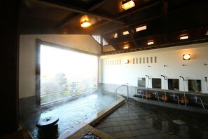 A traditional Japanese onsen with a large hot spring, tiled floor, and a view of a garden through a large window. - Iwamurasansou (Ena)