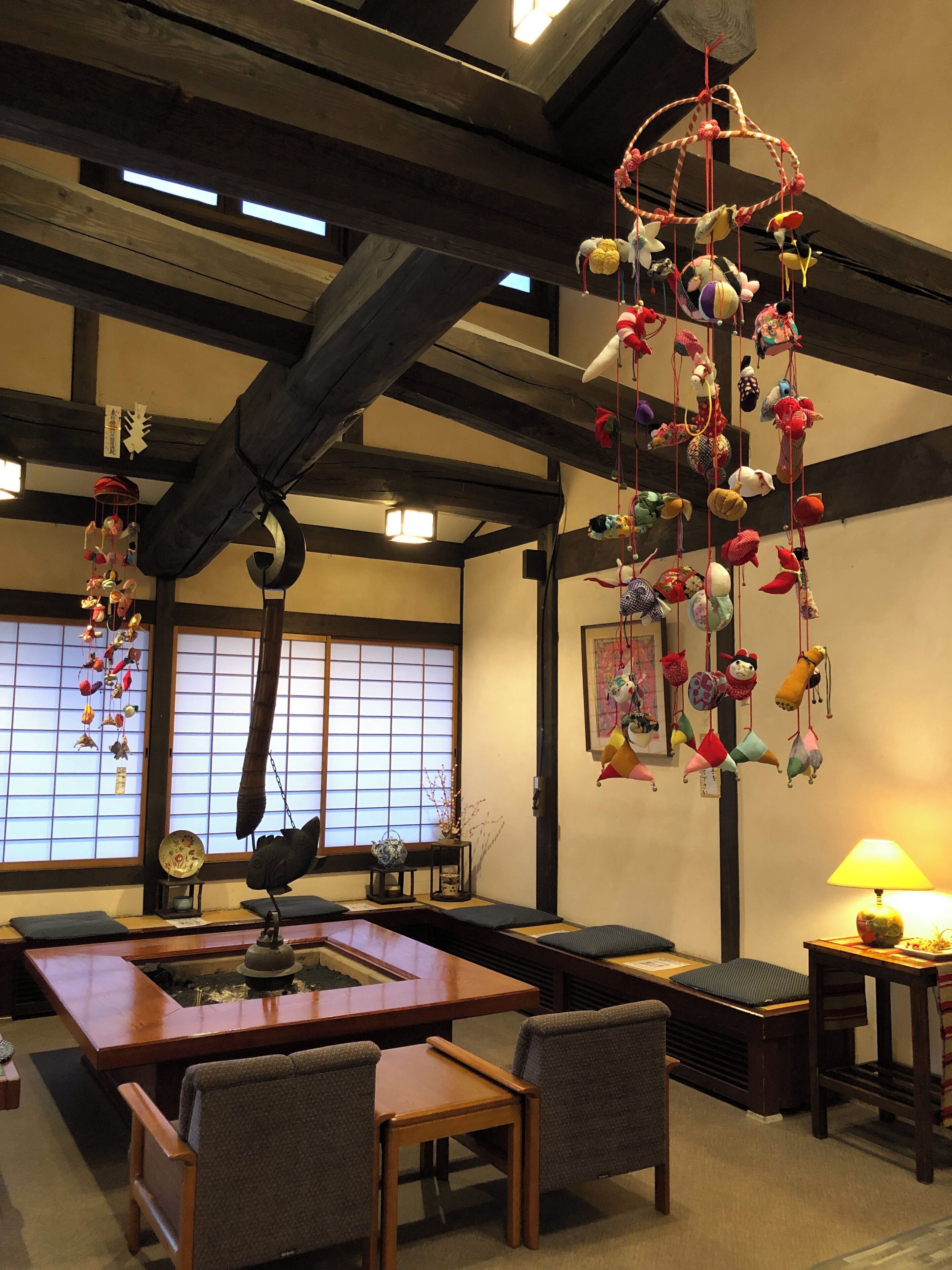 Una habitación tradicional japonesa con suelo de tatami, una mesa de madera baja y un adorno colgante con varios objetos.