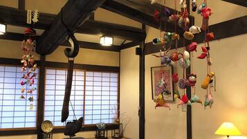 Una habitación tradicional japonesa con suelo de tatami, una mesa de madera baja y un adorno colgante con varios objetos.