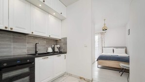 A modern kitchen with white cabinets, a black countertop, and a built-in oven. - Modern Studio in the Center | Balcony | Close to Market Square (Wroclaw)