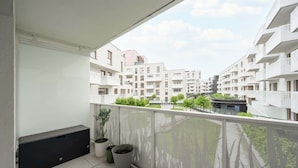 A balcony with a view of modern apartment buildings, potted plants, and a white railing. - Modern Studio in the Center | Balcony | Close to Market Square (Wroclaw)