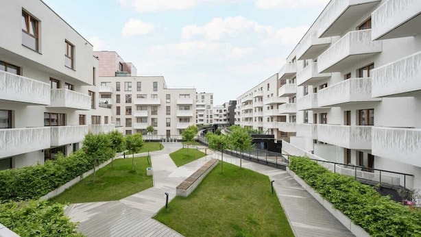 A modern apartment complex with multiple balconies, a central courtyard with grass and trees, and a pedestrian pathway. - Modern Studio in the Center | Balcony | Close to Market Square (Wroclaw)