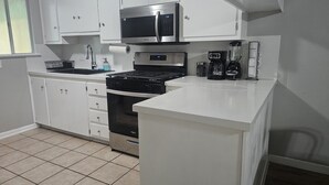 A compact kitchen with a microwave, stove, oven, and coffee maker. - ENTIRE UNIT | 2BR | Washer/Dryer | Sleeps 6 | Near Airport (Austin)