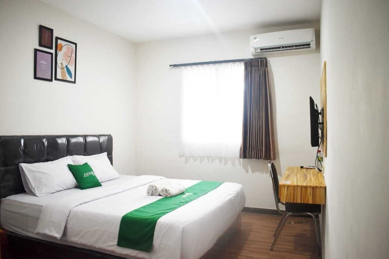 A hotel room with a bed, a desk, a chair, and a window with curtains.