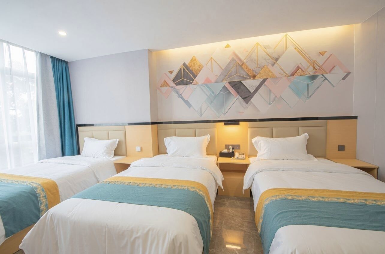 Une chambre d’hôtel avec trois lits, une grande œuvre d’art abstrait accrochée au mur et une fenêtre avec des rideaux.