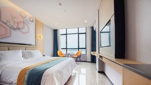A modern hotel room with a large bed, a desk, two chairs, and a large window offering a view. - Kelley Hotel (Wuzhou)