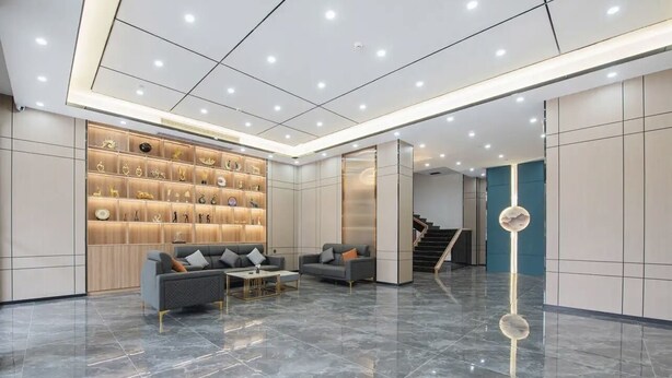 A modern lobby with a marble floor, two sofas, a coffee table, and a wall display of decorative items. - Kelley Hotel (Wuzhou)