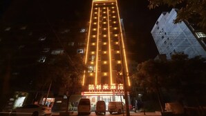 A hotel with a modern design, featuring a prominent vertical light display and a clear sign indicating its name and services. - Kelley Hotel (Wuzhou)