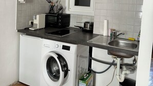 A compact kitchen with a washing machine, microwave, and sink.