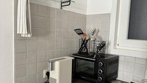 A kitchen with a toaster, a microwave, and a stove. There are kitchen utensils and a bottle on the counter.