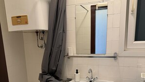 A bathroom with a white sink, a mirror, a shower curtain, and a toilet.
