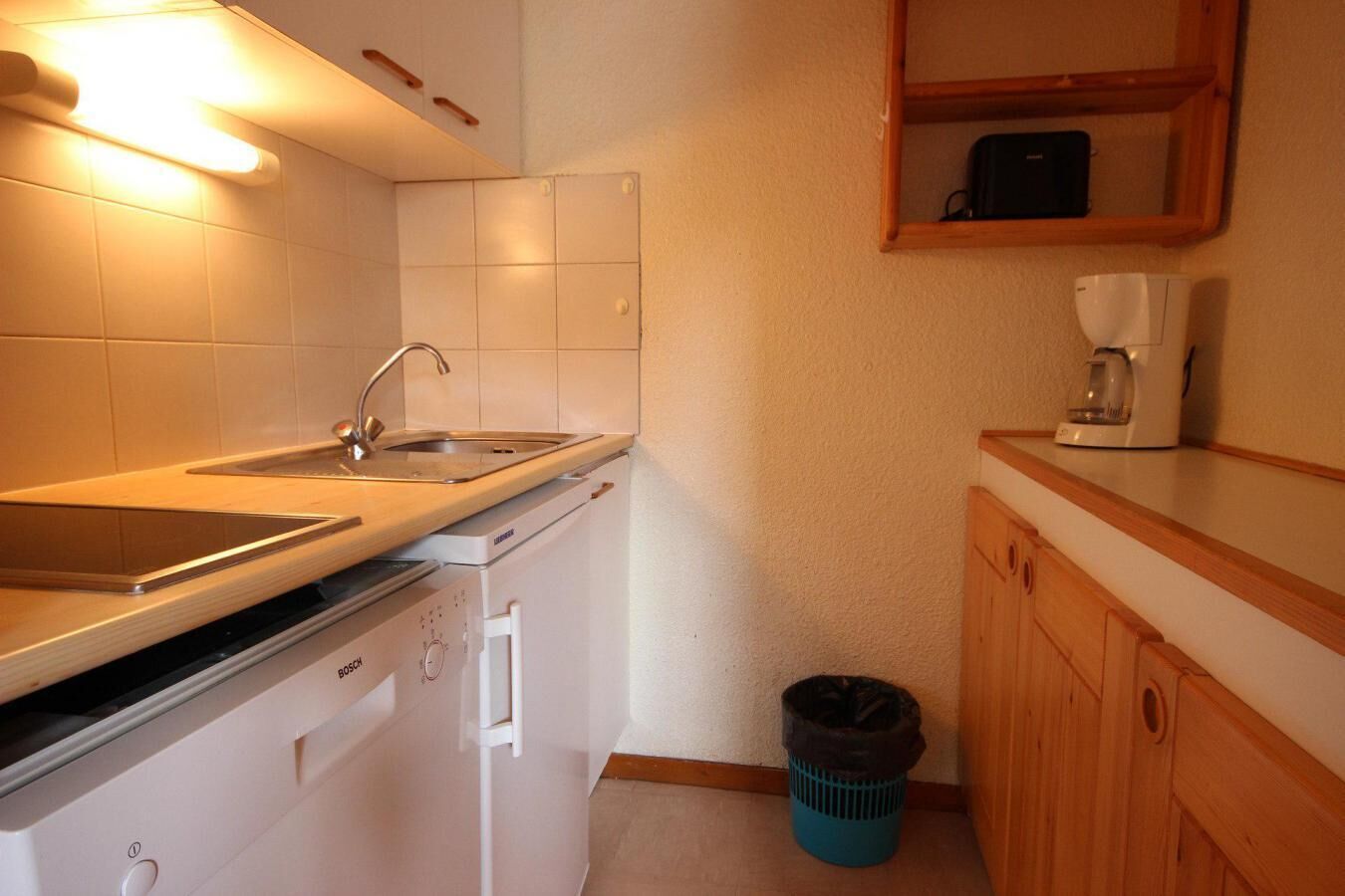 A compact kitchen with a Bosch dishwasher, a sink, and a coffee maker on the countertop.