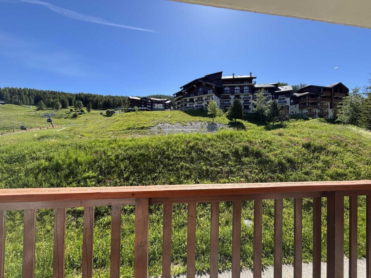 A hotel with multiple floors, a balcony, and a view of a green landscape.