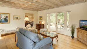 Un salón espacioso con un sofá azul, una mesa de centro de madera y un televisor sobre un mueble de madera.