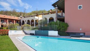 A swimming pool with a clear blue water surface, surrounded by a paved walkway. - Apartment Ponte Tesina (Costermano)