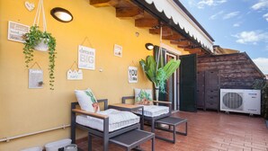 A cozy outdoor seating area with two cushioned chairs and a table, a potted plant, and a wall with motivational signs. - Apartment Ponte Tesina (Costermano)