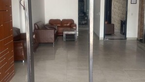 A spacious living area with a modern design, featuring a sofa set, a coffee table, and a decorative metal structure in the foreground. - Hotel Avalon Palace  (New Delhi)