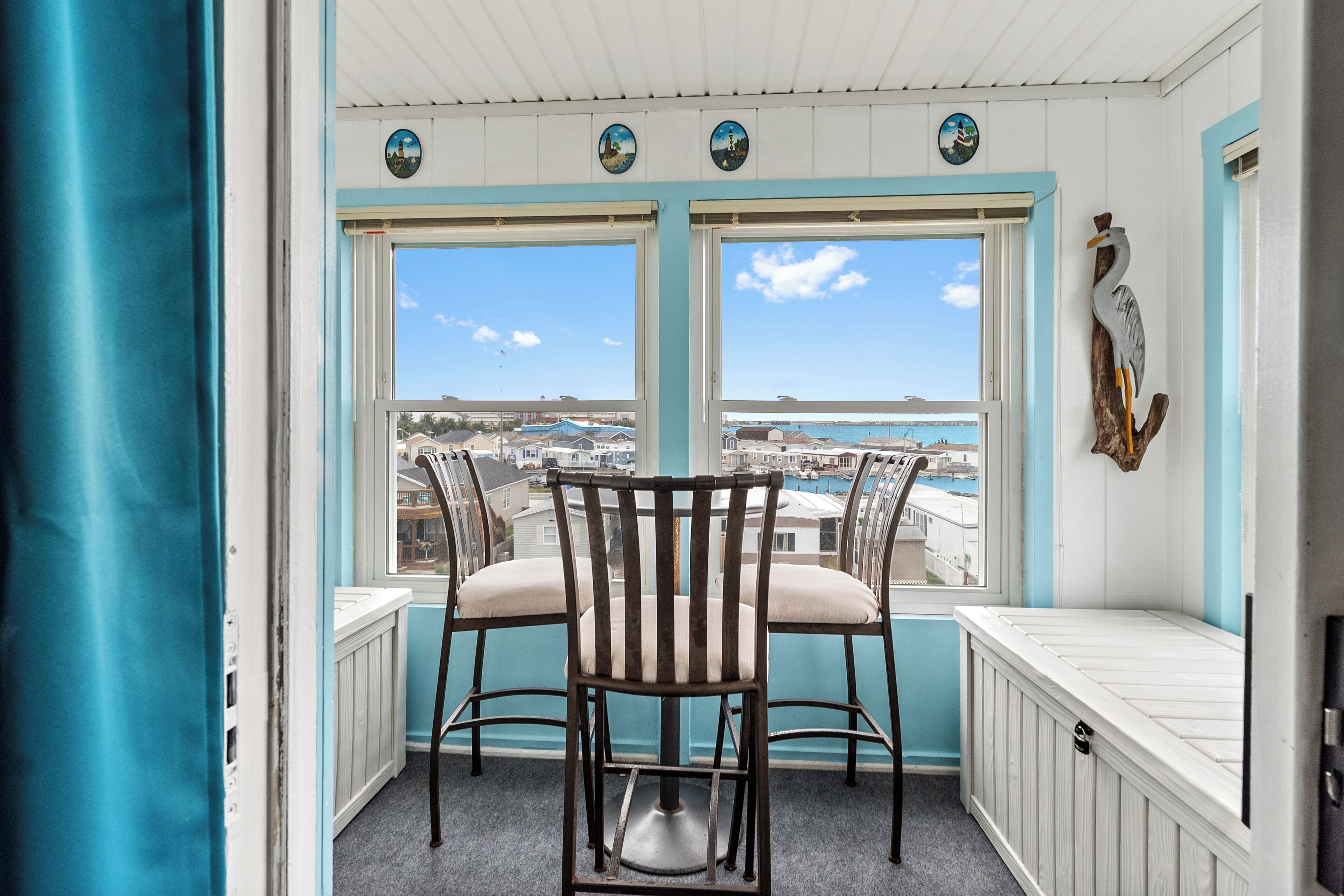 A balcony with two chairs, a view of the sea, and a decorative seagull.