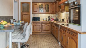 A kitchen with wooden cabinets, a microwave, a toaster, and a refrigerator. - Charming Winemaker's House in Castle Heartland, Terrace and Modern Comfort (Sambin)