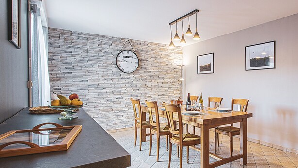 A dining area with a brick wall, wooden table, chairs, and a clock. - Charming Winemaker's House in Castle Heartland, Terrace and Modern Comfort (Sambin)
