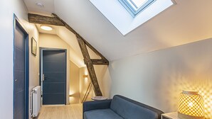 A compact room with a sloped ceiling, a built-in bench, a small table with a lamp, and a door leading to another room. - Charming Winemaker's House in Castle Heartland, Terrace and Modern Comfort (Sambin)