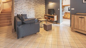 A modern living room with a stone wall, a sofa, a coffee table, and a TV stand. - Charming Winemaker's House in Castle Heartland, Terrace and Modern Comfort (Sambin)