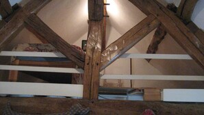 A loft bedroom with exposed wooden beams, a sloped ceiling, and a bed with patterned bedding. - Cottage with pond and boat, relaxation in Sologne (Saint-Viâtre)