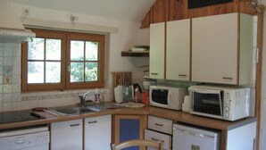 A compact kitchen with white cabinets, a microwave, a toaster, and a dishwasher. - Cottage with pond and boat, relaxation in Sologne (Saint-Viâtre)