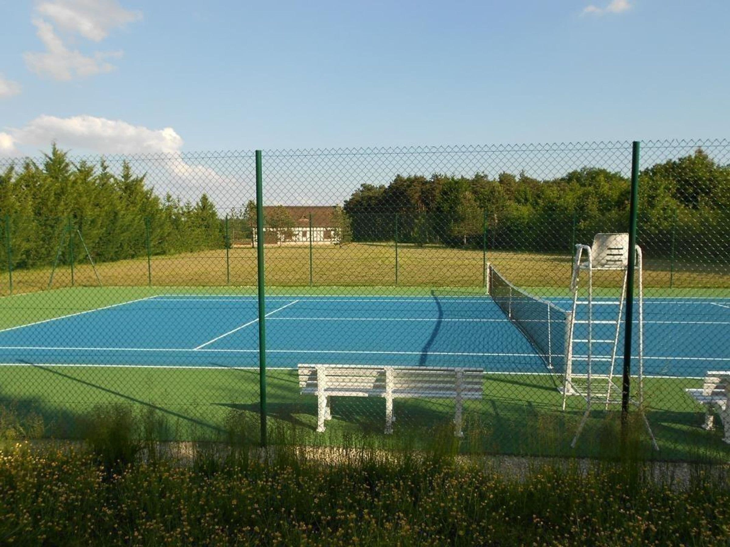 A tennis court with a net, a bench, and a ladder.